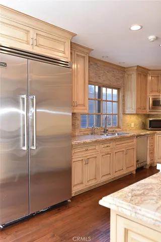 a kitchen with granite countertop stainless steel appliances a refrigerator stove top oven and sink