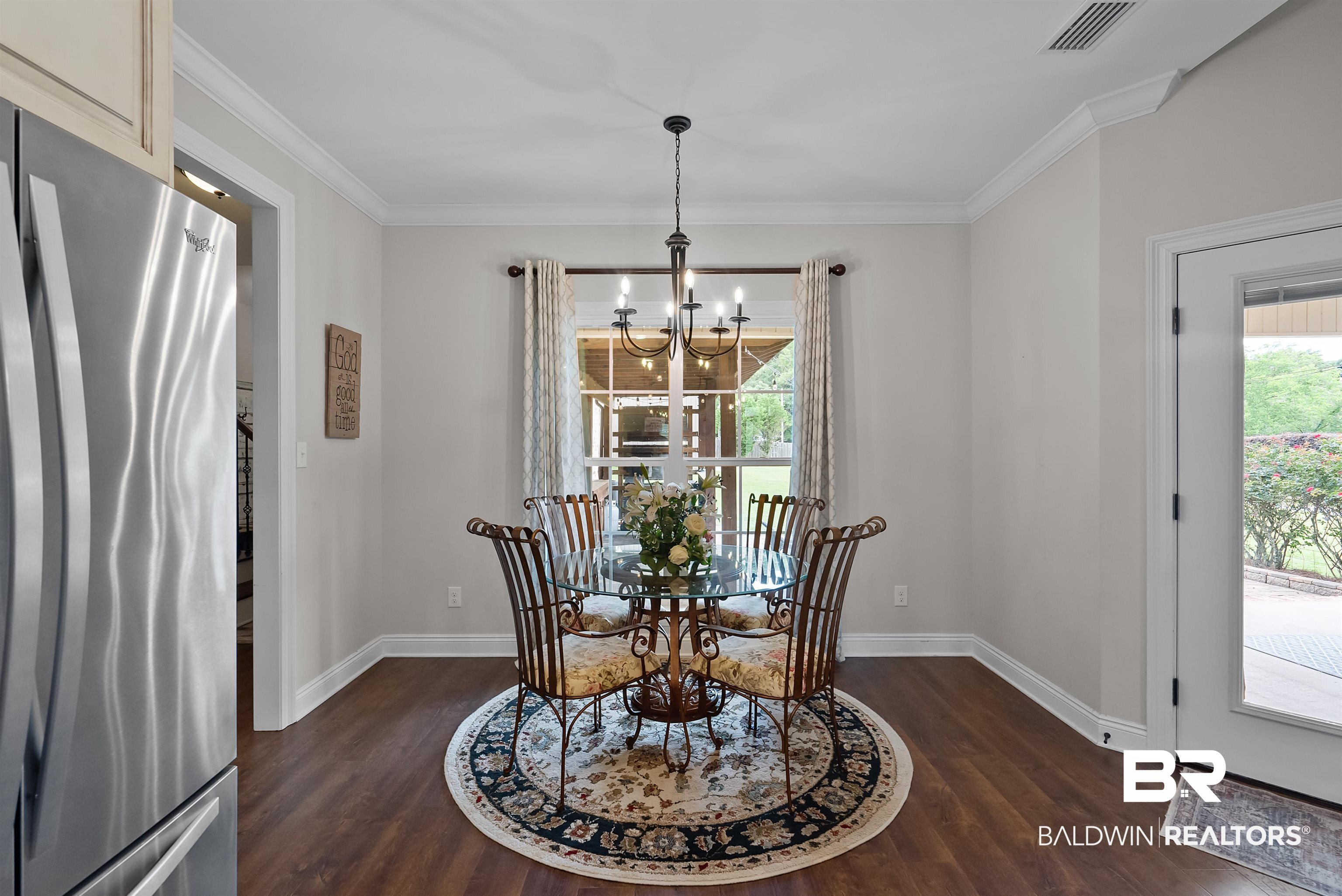 12070 Comalander Road Fairhope, AL 36532 - Photo 16 of 50 Dining space featuring wood-finish flooring, crown molding, and a chandelier