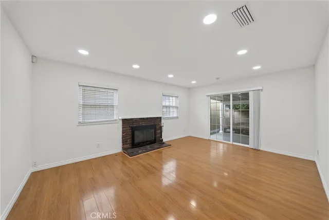 a view of empty room with wooden floor and fireplace