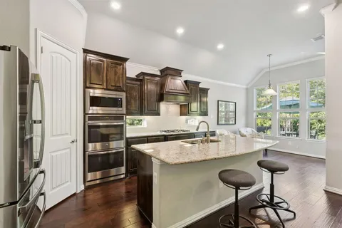 a kitchen with stainless steel appliances granite countertop a refrigerator a stove and a sink