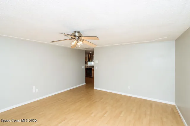 an empty room with a ceiling fan and wooden floor