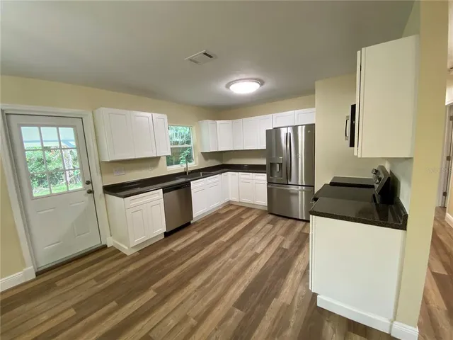 a kitchen with granite countertop a refrigerator and a stove top oven