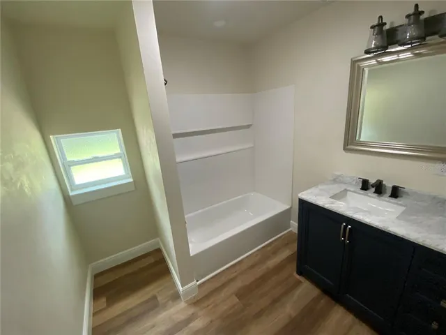 a bathroom with a tub sink vanity and mirror