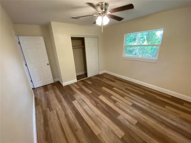 a view of empty room with wooden floor and fan