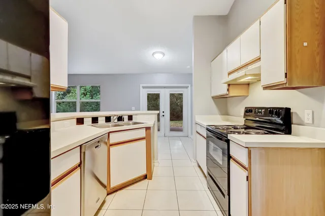 a kitchen with stainless steel appliances a stove a sink and white cabinets