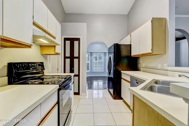 a kitchen that has a sink wooden cabinets and stainless steel appliances