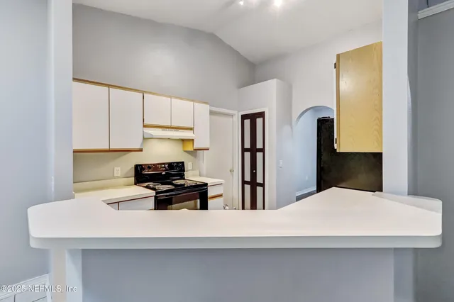 a kitchen with stainless steel appliances a stove a refrigerator white cabinets and wooden floor