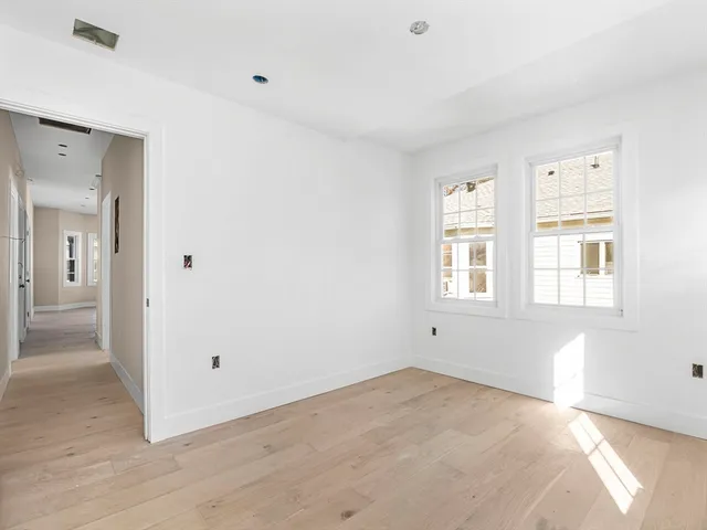 a view of empty room with wooden floor and windows