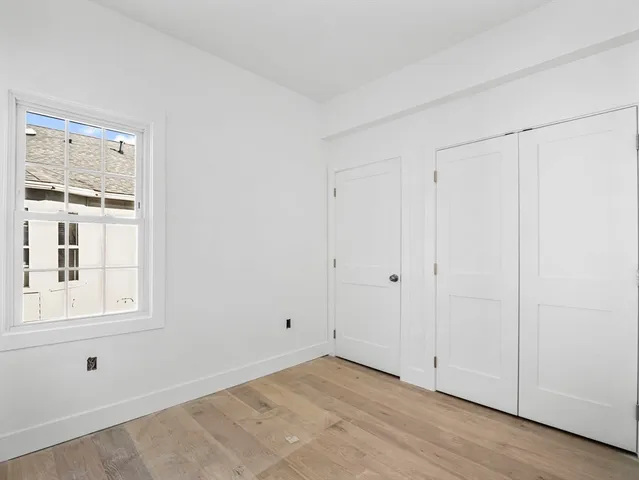 a view of an empty room with wooden floor and closet