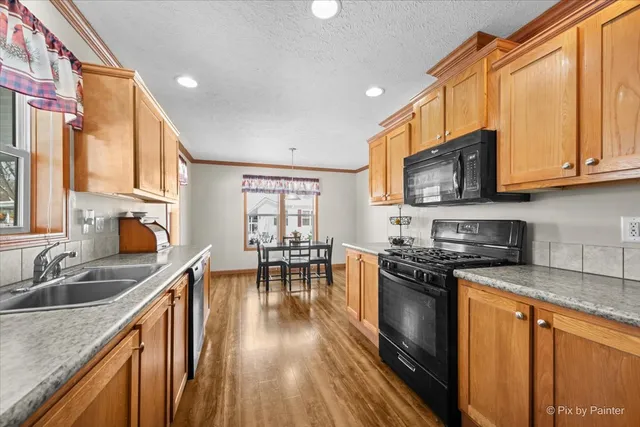 a kitchen with stainless steel appliances granite countertop a stove top oven a sink a dining table and chairs