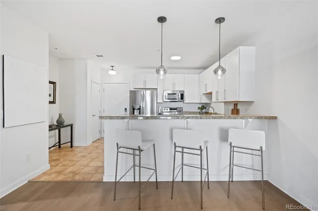 a kitchen with stainless steel appliances granite countertop a table chairs stove and white cabinets