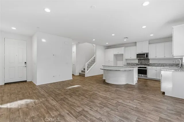 a view of kitchen with granite countertop kitchen island white cabinets and stainless steel appliances