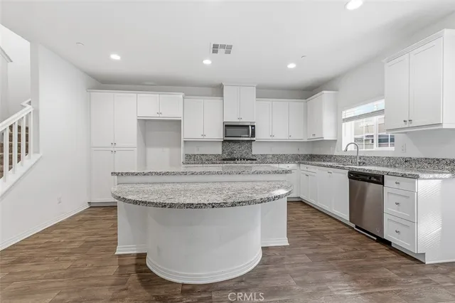 a large kitchen with granite countertop a sink a counter top space and cabinets