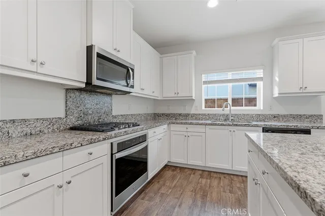a kitchen with granite countertop cabinets stainless steel appliances and a sink