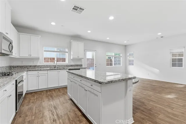 a kitchen with stainless steel appliances granite countertop a lot of counter space and wooden floors