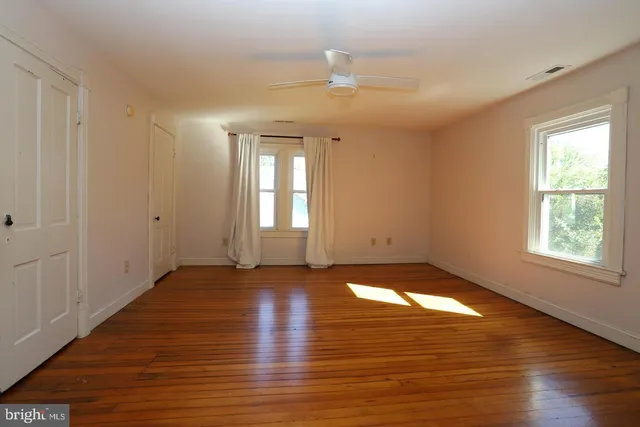 an empty room with wooden floor and windows