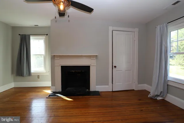 a view of a livingroom with wooden floor and a fireplace