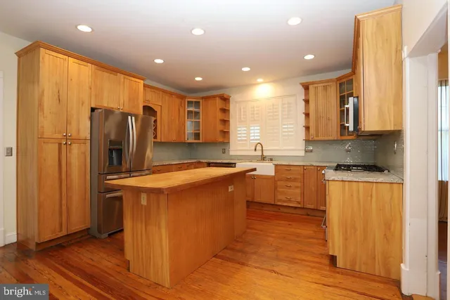 a kitchen with stainless steel appliances granite countertop a refrigerator a sink dishwasher and a stove with wooden floor