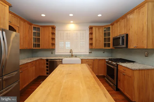 a large kitchen with stainless steel appliances granite countertop a stove a sink and a microwave