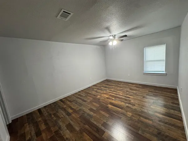 an empty room with a chandelier fan and windows