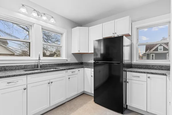 a kitchen with granite countertop white cabinets and refrigerator