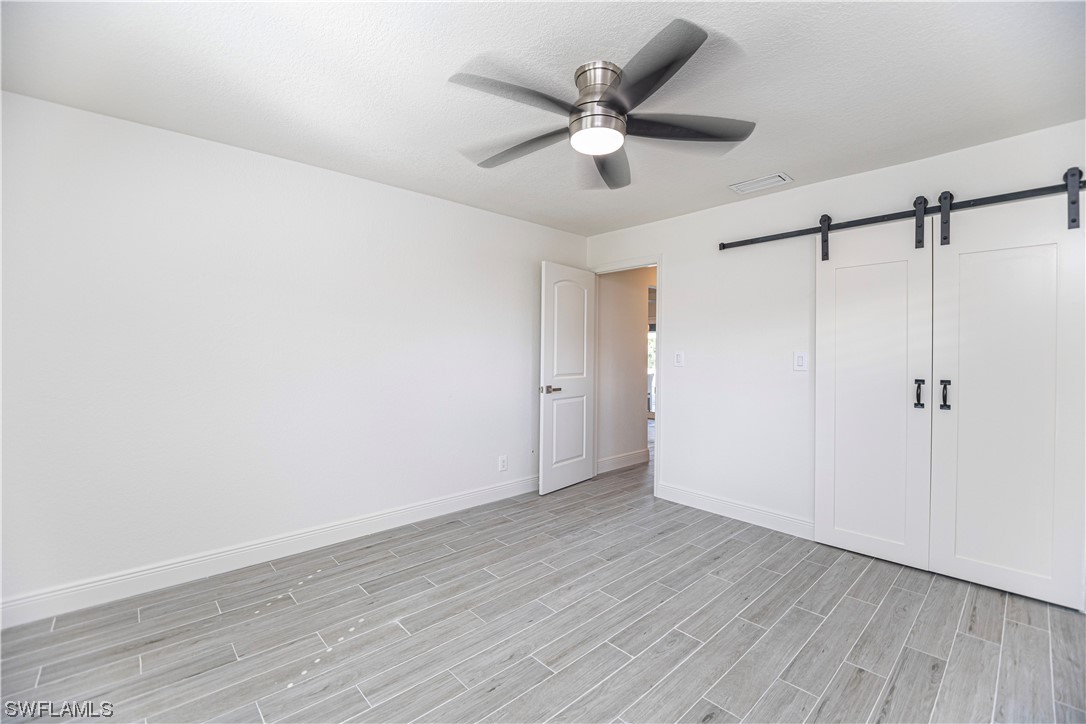 1753 Club House Road North Fort Myers, FL 33917 - Photo 21 of 24 an empty room with wooden floor fan and windows