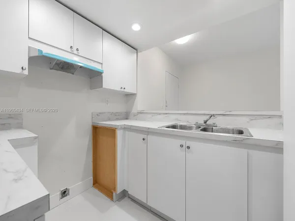 a kitchen with granite countertop white cabinets and sink