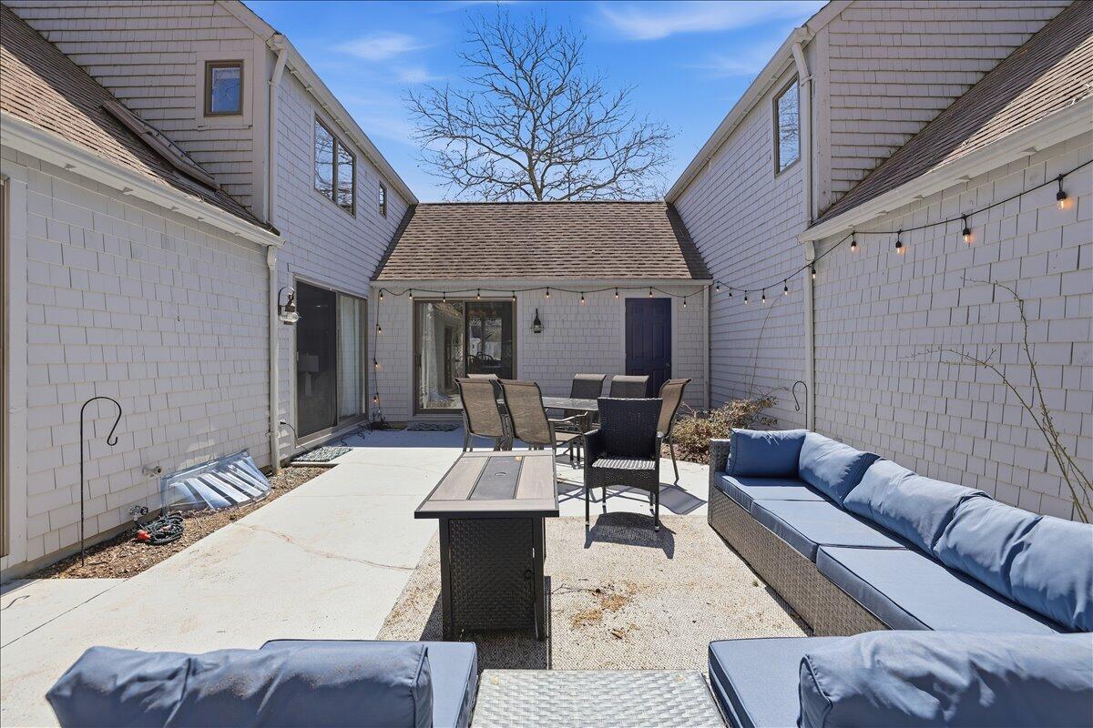 100 Mid-Iron Way, Unit 7027 Mashpee, MA 02649 - Photo 25 of 38 a view of a patio with couches table and chairs with wooden floor and fence