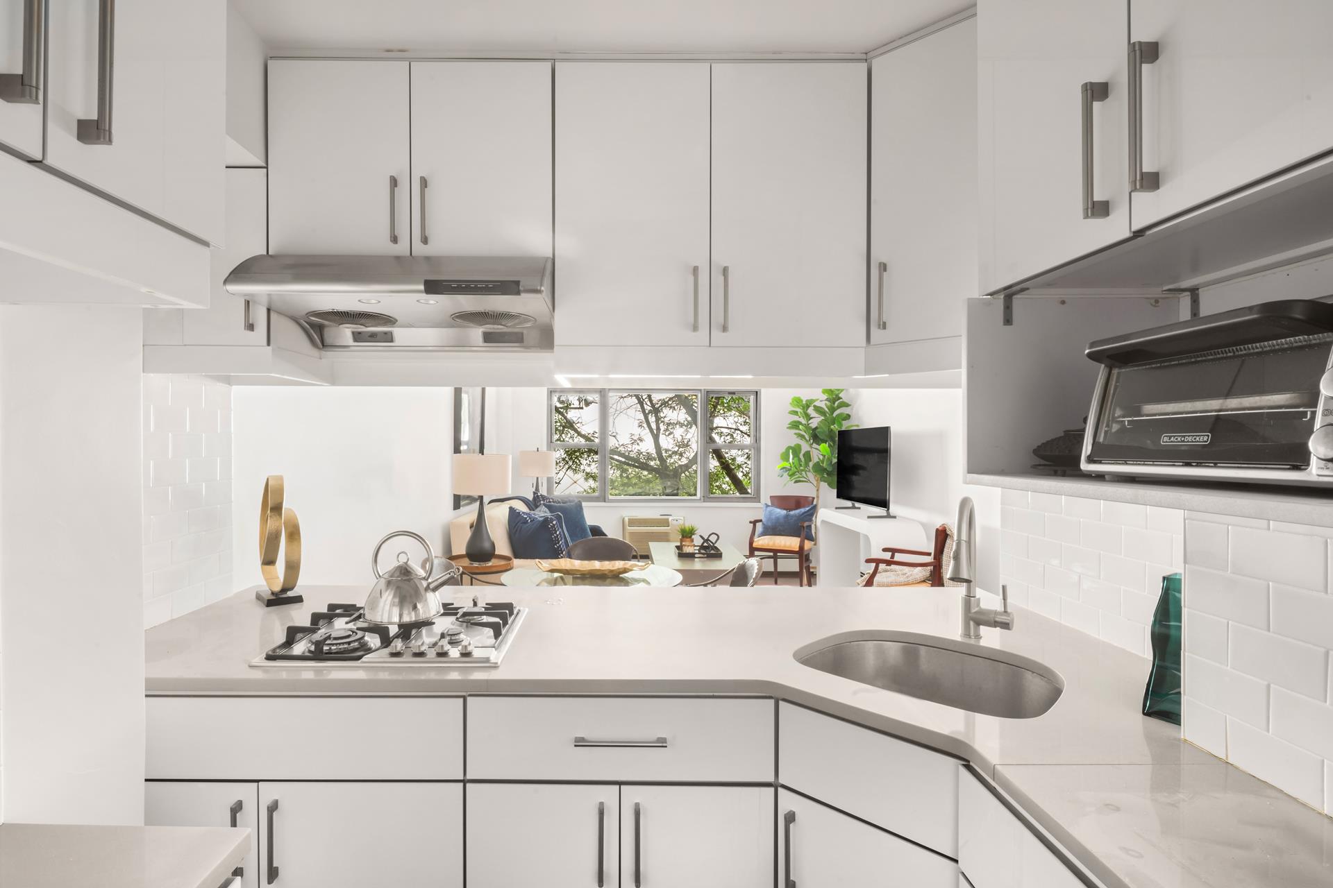 40 Sutton Place, Unit 3F Manhattan, NY 10022 - Photo 5 of 9 a kitchen with kitchen island granite countertop white cabinets and white appliances