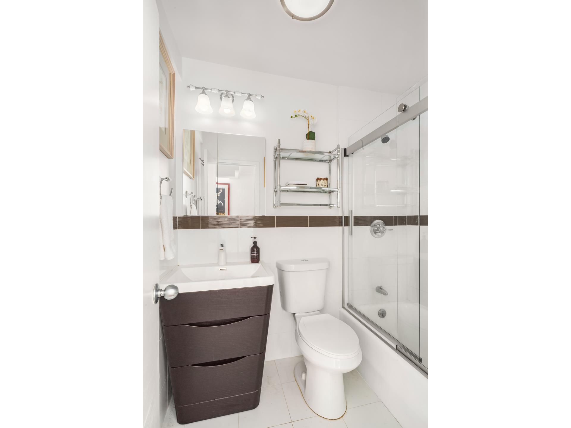 40 Sutton Place, Unit 3F Manhattan, NY 10022 - Photo 8 of 9 a bathroom with a toilet a sink and mirror