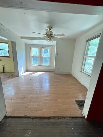 a view of an empty room with window and chandelier fan