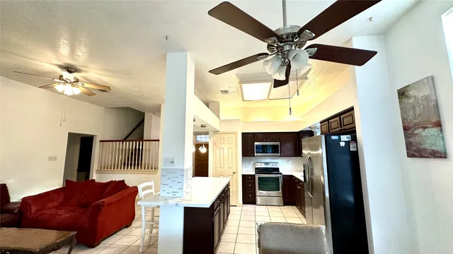 a living room with stainless steel appliances furniture and a chandelier
