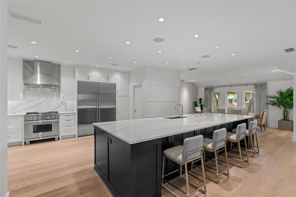 6117 Merrymount Road Westover Hills, TX 76107 - Photo 14 of 39 Two tone kitchen featuring dual tone cabinets, premium appliances, a large island with sink, light stone counters, and recessed lighting