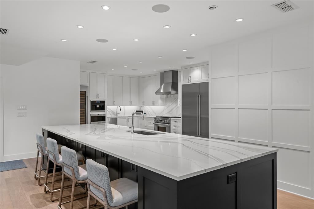 6117 Merrymount Road Westover Hills, TX 76107 - Photo 15 of 39 Dual tone kitchen featuring light wood-style flooring, a large island with sink, light stone countertops, recessed lighting, and premium appliances