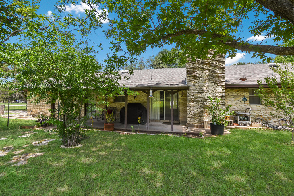 301 Navajo Trail Georgetown, TX 78633 - Photo 17 of 35 Back of property featuring a patio area, a lawn, a chimney, and roof with shingles