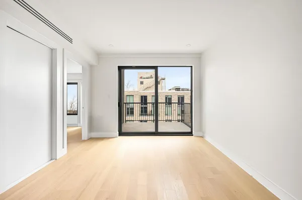 a view of a hallway with wooden floor and a bathroom