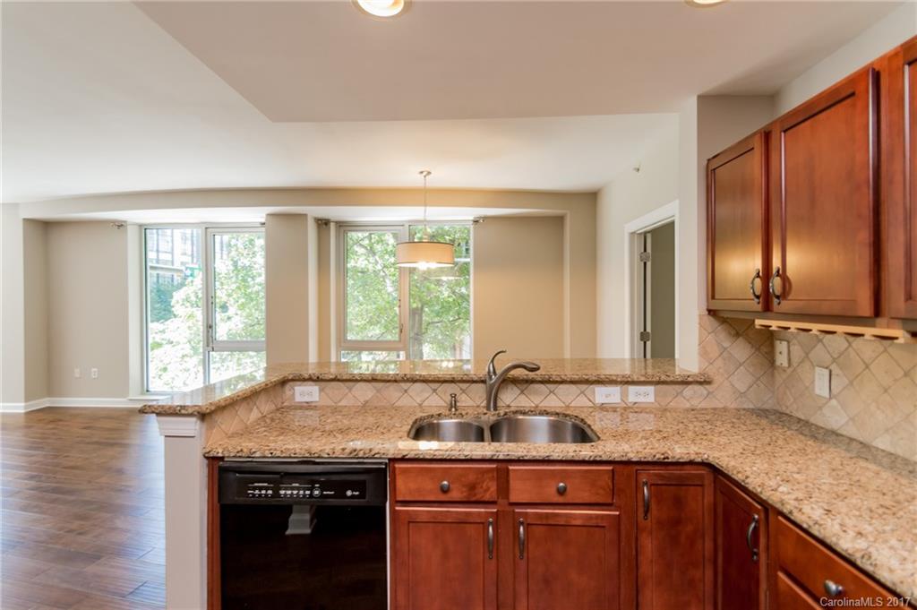 718 West Trade Street, Unit 211 Charlotte, NC 28202 - Photo 2 of 24 a kitchen with stainless steel appliances granite countertop a sink a stove and a wooden cabinets