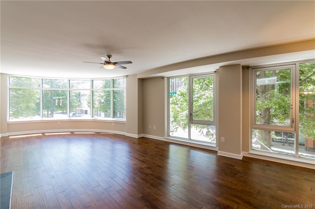 718 West Trade Street, Unit 211 Charlotte, NC 28202 - Photo 4 of 24 a view of an empty room with wooden floor and a large window
