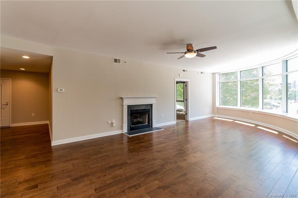 718 West Trade Street, Unit 211 Charlotte, NC 28202 - Photo 5 of 24 an empty room with wooden floor fireplace and windows