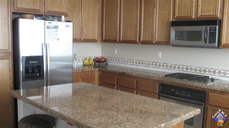 44741 Ruthron Avenue Lancaster, CA 93536 - Photo 11 of 18 a kitchen with stainless steel appliances granite countertop a refrigerator a stove and a sink with wooden cabinets