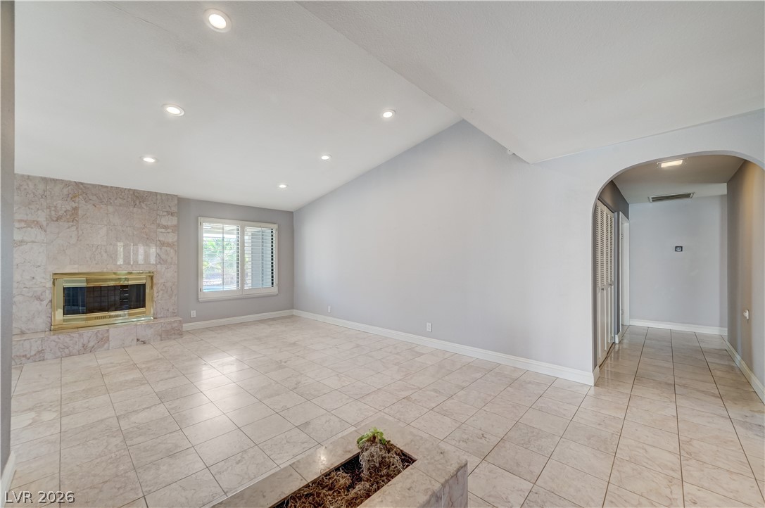 6635 Costa Brava Road Las Vegas, NV 89146 - Photo 8 of 59 A spacious living area features a grand marble fireplace and elegant tiled flooring, illuminated by recessed lighting.