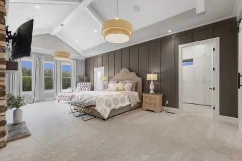 a spacious bedroom with a bed a flat screen tv and balcony