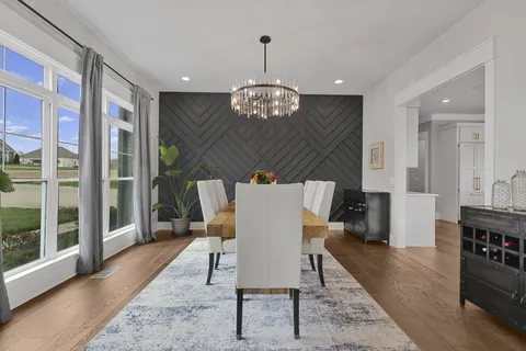 a dining room filled chandelier and wooden floor