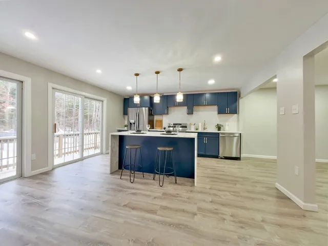 a large kitchen with stainless steel appliances granite countertop a large counter top a sink and a refrigerator