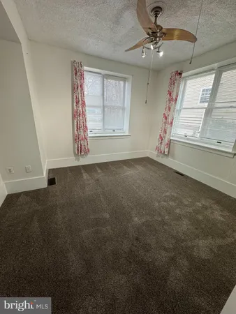 en empty room with windows and ceiling fan
