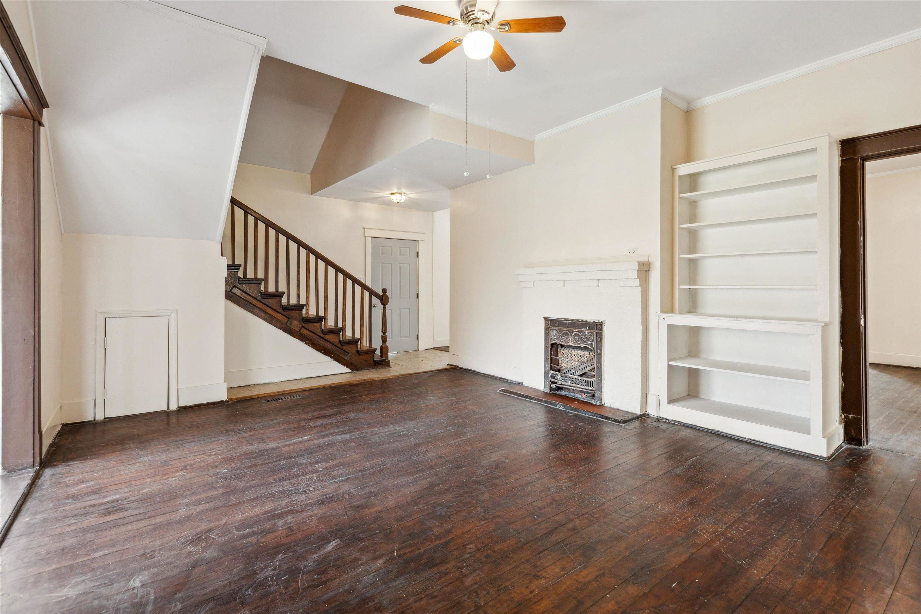 8457 East Kerrville Rosemark Road Millington, TN 38053 - Photo 3 of 32 Unfurnished living room with dark wood-style floors, ceiling fan, built in features, crown molding, and a fireplace with raised hearth
