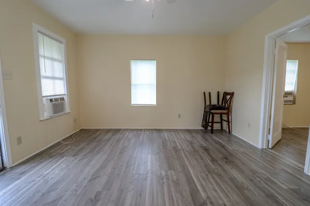 an empty room with wooden floor and windows