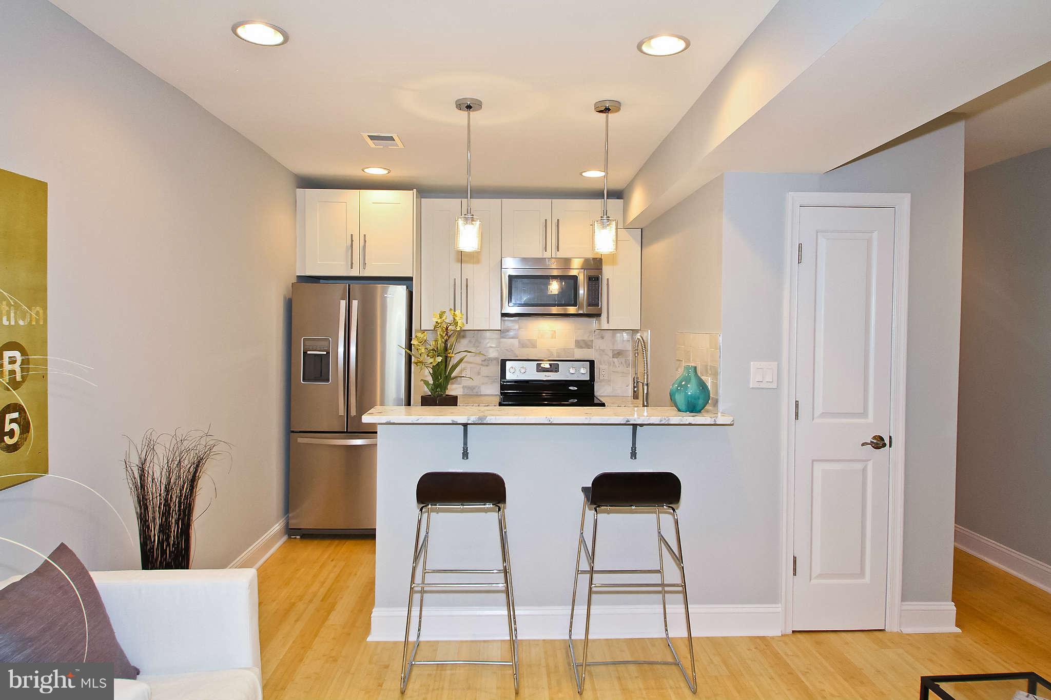 604 Columbia Road Northwest, Unit 1 Washington, DC 20001 - Photo 4 of 17 a kitchen with stainless steel appliances kitchen island granite countertop a refrigerator a stove a sink dishwasher and white cabinets with wooden floor