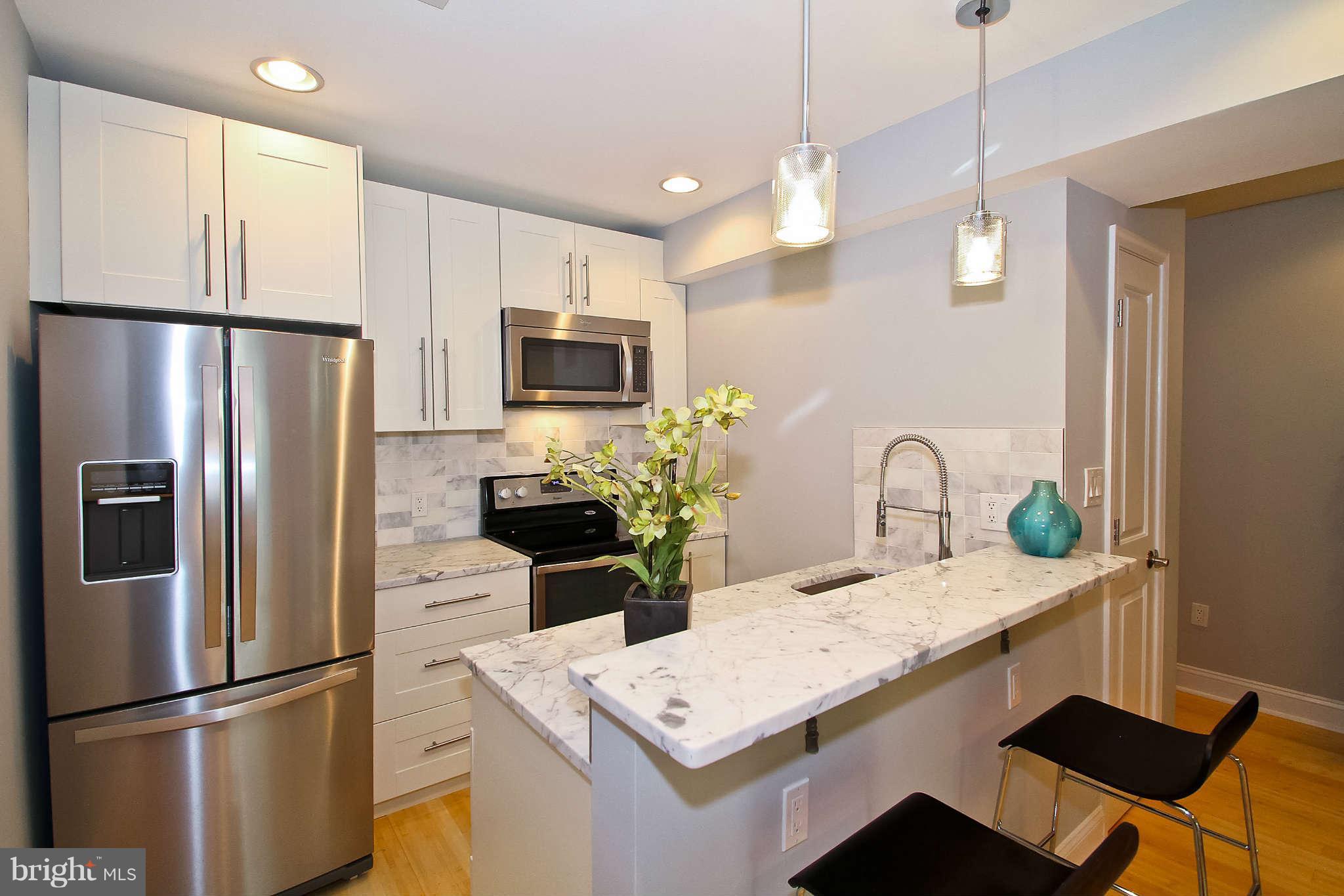604 Columbia Road Northwest, Unit 1 Washington, DC 20001 - Photo 5 of 17 a kitchen with stainless steel appliances granite countertop a refrigerator a sink a stove a dining table and chairs