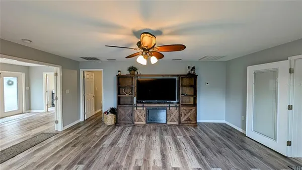 a view of a livingroom with wooden floor a flat screen tv and windows